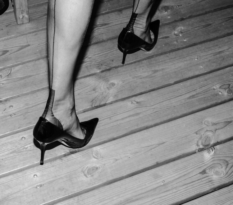 eine Frau geht in Stöckelschuhen und Damenstrümpfen auf einer Terasse. es sind echte Nahtnylons