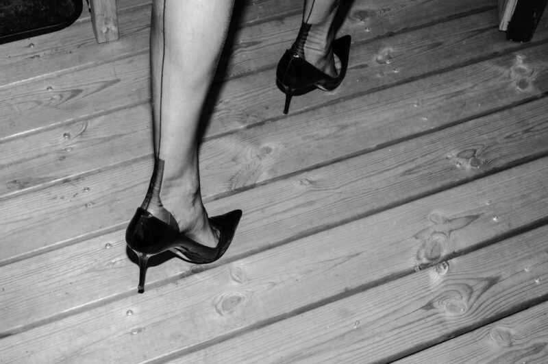 eine Frau geht in Stöckelschuhen und Damenstrümpfen auf einer Terasse. es sind echte Nahtnylons