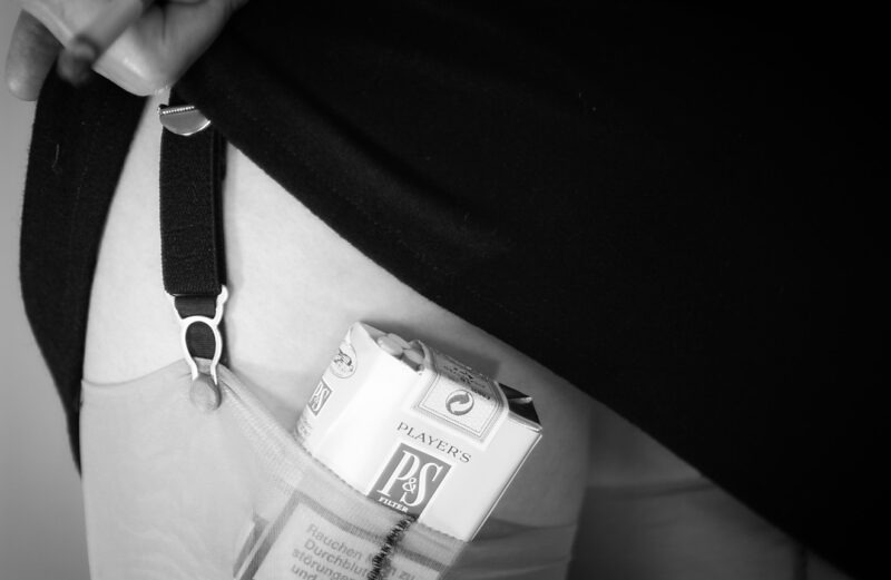 Cigarettes & Nylons. Ein Modell hat eine Schachtel Zigaretten in ihrem Strumpf