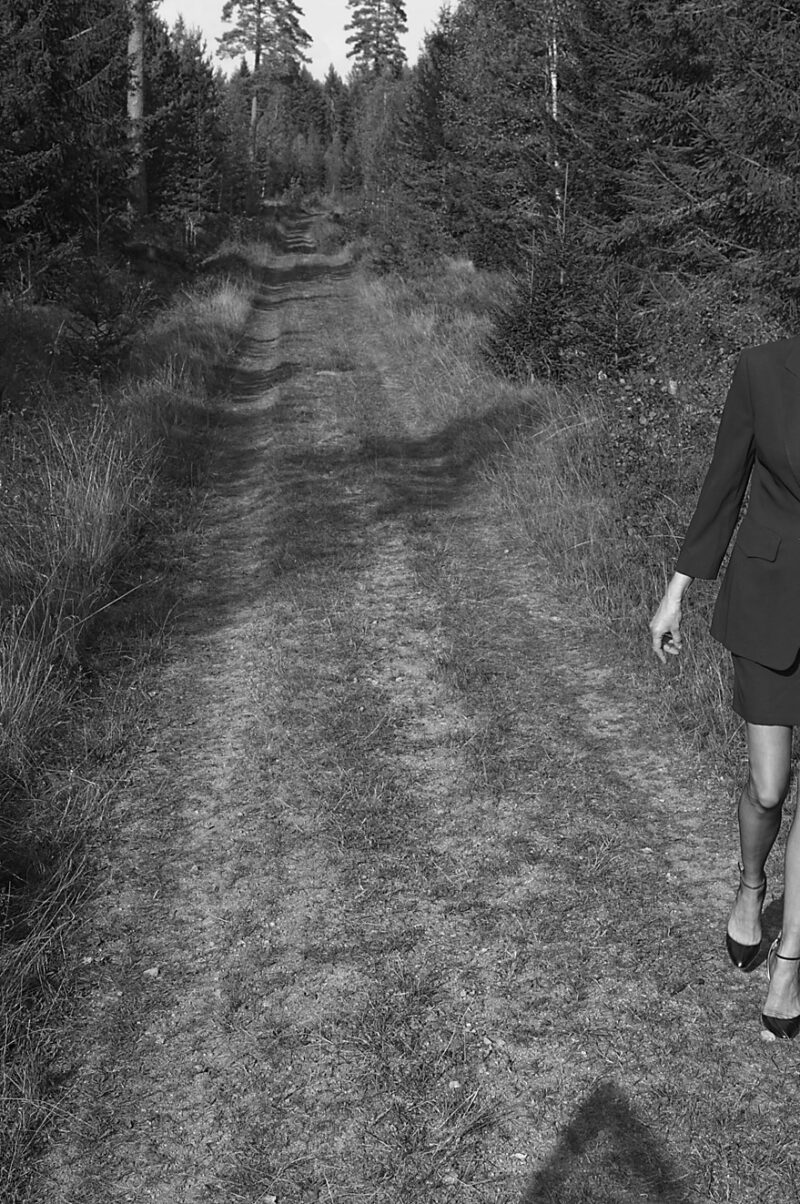 Ein Modell in Nylons geht auf einem Waldweg. Das Modell Lilly Svart ist nur am Rande zu erkennen