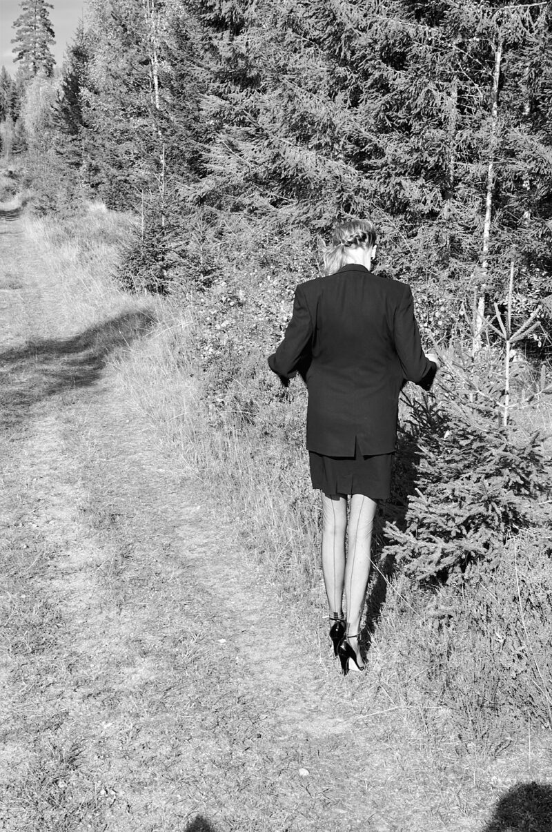 Ein Modell trägt Strümpfe und High Heels im Wald.