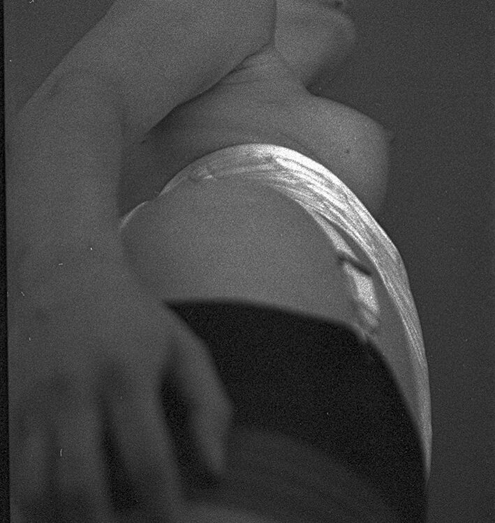 Strumpfansatz mit Strumpfhaltern von untern fotografiert. Leicht zu erkennen eine weibliche Brust.