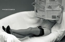 Year 2009: Corset Eine Frau liest in Damenstrümpfen und Korsett gekleidet eine Tageszeitung. Dabei liegt sie auf einem Sofa.