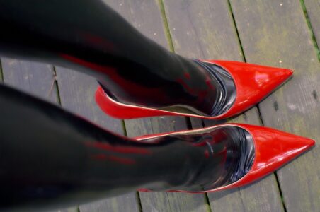"Comfort Size" Version Black AG Nahtstrumpf latex stockinged legs and feets and red Jimmy Choo High Heels. The Heels standing on a wooden floor